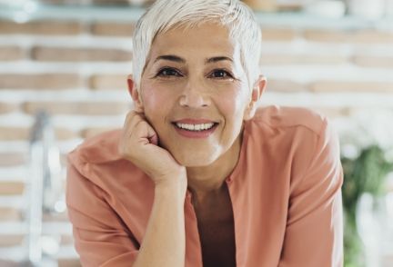 A woman over 50 with her chin resting on her hand looking into the camera