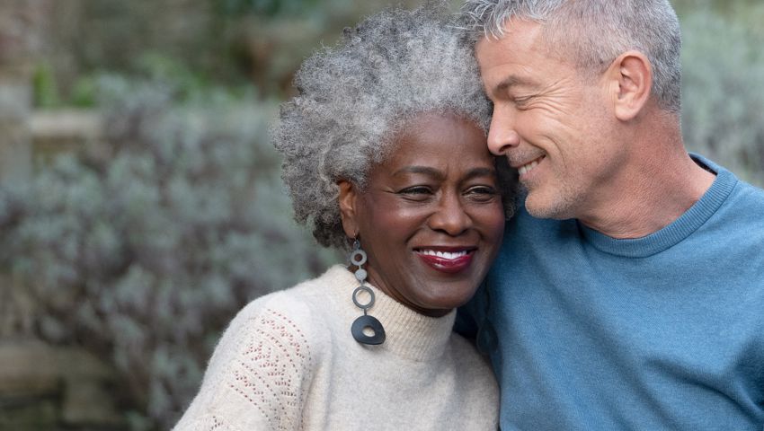 A male and female couple smiling a hugging in a garden